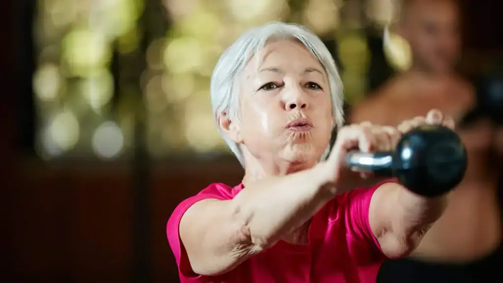 Older woman doing weight training Rhyl to help her strength and longevity 