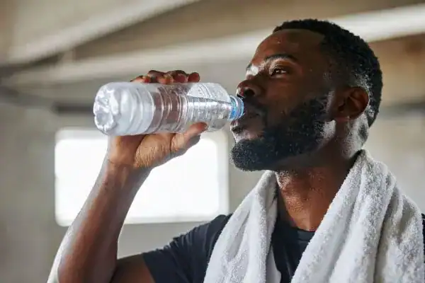 Image of man drinking water to improve hydration Rhyl after work out.